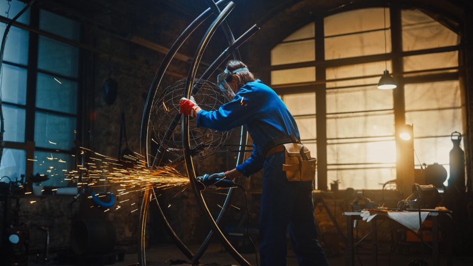 man-blue-suit-is-working-metal-wheel-with-light-background